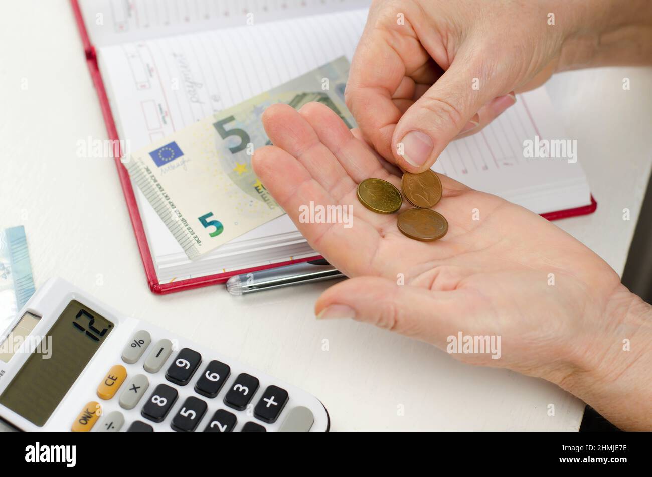 Il pensionato sta calcolando il profitto. Depositi pensionistici. Centesimi di Euro in vecchie mani femminili. Foto Stock