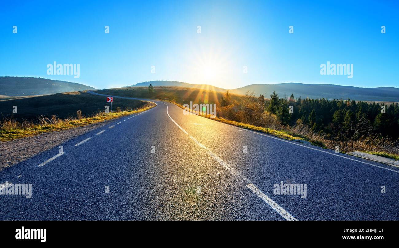 Strada asfaltata di alta qualità in montagna. Con marcature e infrastrutture stradali al tramonto. Foto Stock