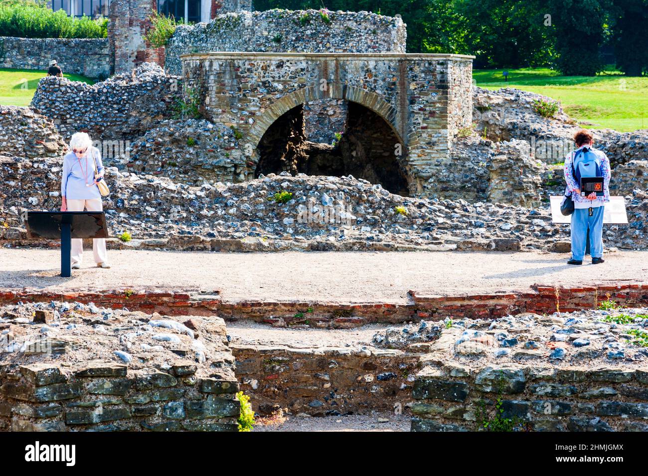 Due donne, turisti, che si levano in piedi separatamente per leggere le bacheche informative presso le rovine dell'Abbazia di St Augustine a Canterbury in sole brillante. Foto Stock