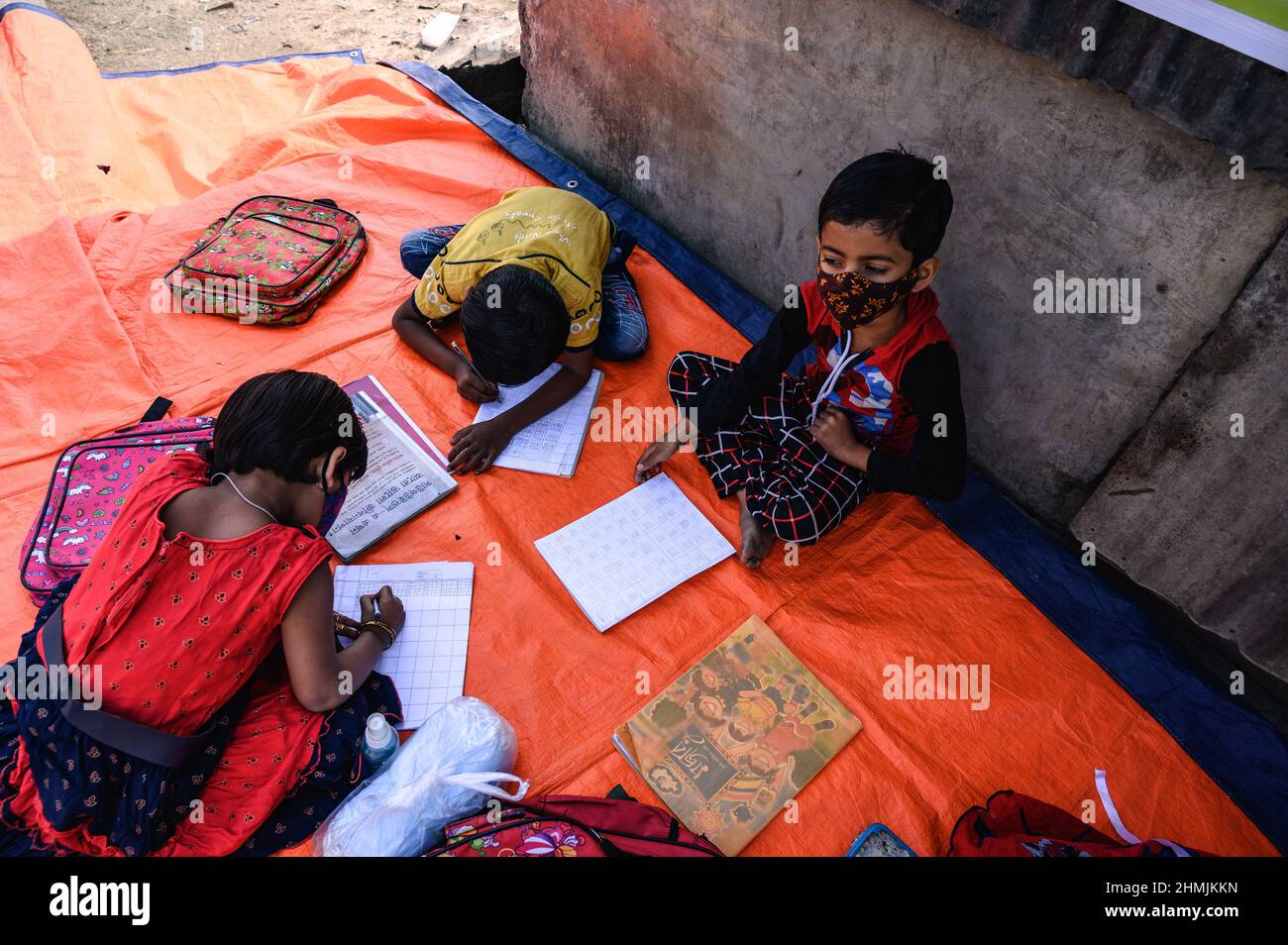 Una classe della scuola elementare sul confine India-Bangladesh è condotta su una strada vuota accanto alla recinzione a Nabin Nagar, nel Bengala occidentale. Il governo del Bengala occidentale ha lanciato “Paray Shikshalaya”, un programma di scolarizzazione basato sulla comunità rivolto agli studenti primari che hanno abbandonato il sistema di istruzione formale negli ultimi due anni a causa della chiusura delle scuole a causa del Covid-19. India. Foto Stock