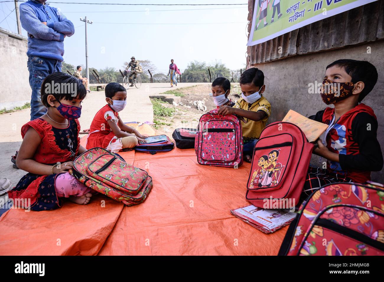 Una classe della scuola elementare sul confine India-Bangladesh è condotta su una strada vuota accanto alla recinzione a Nabin Nagar, nel Bengala occidentale. Il governo del Bengala occidentale ha lanciato “Paray Shikshalaya”, un programma di scolarizzazione basato sulla comunità rivolto agli studenti primari che hanno abbandonato il sistema di istruzione formale negli ultimi due anni a causa della chiusura delle scuole a causa del Covid-19. India. Foto Stock