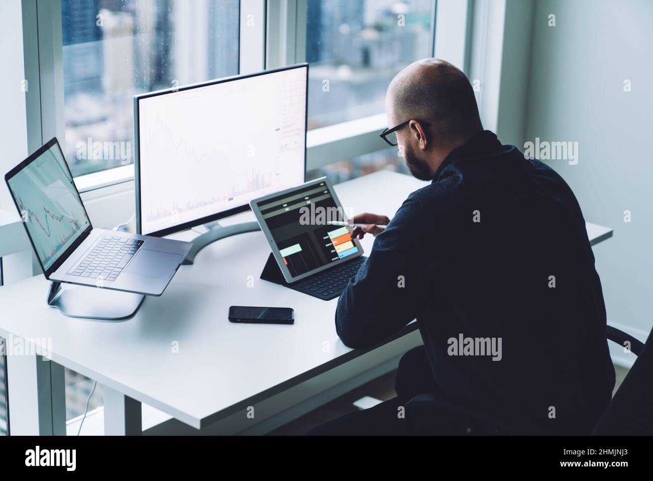 Trader anonimo che analizza i dati su tablet e computer in ufficio Foto Stock