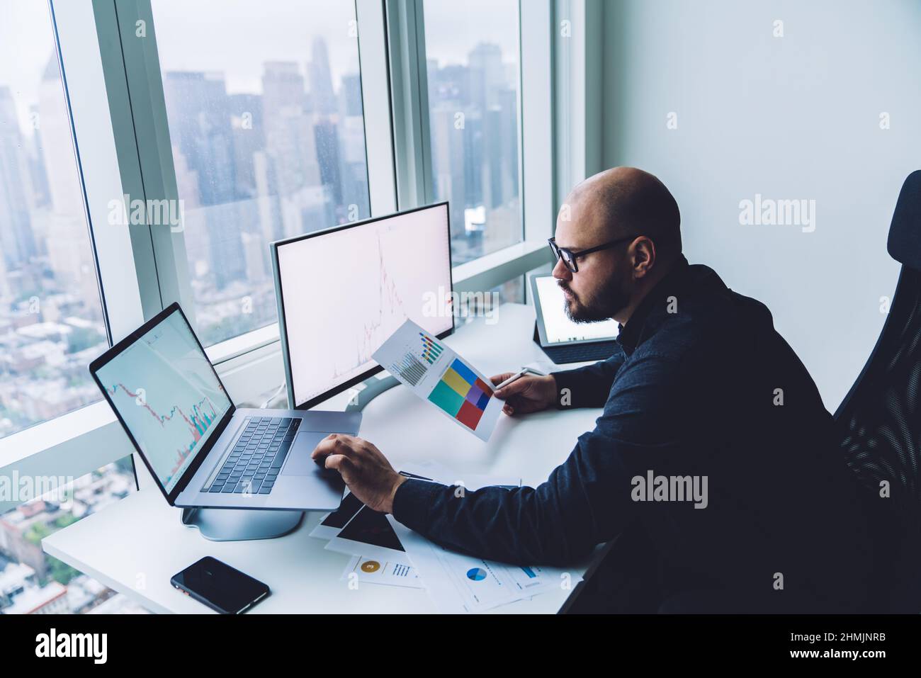 Analista maschile concentrato che lavora su un notebook in un ambiente di lavoro moderno Foto Stock
