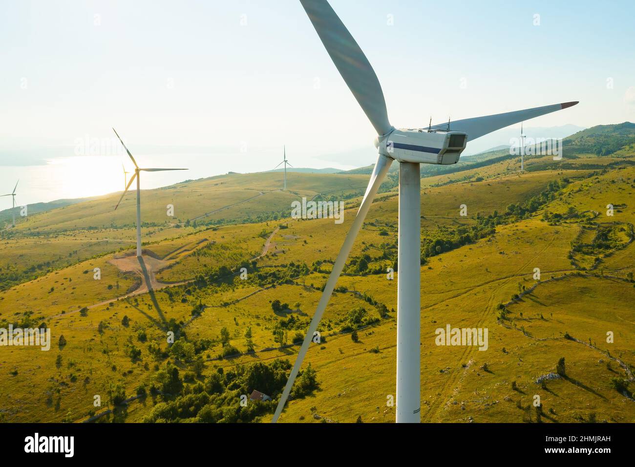 I generatori azionati dal vento con lame operative producono energia rinnovabile sparsa in altopiano vicino al mare Adriatico in vista aerea al mattino presto Foto Stock