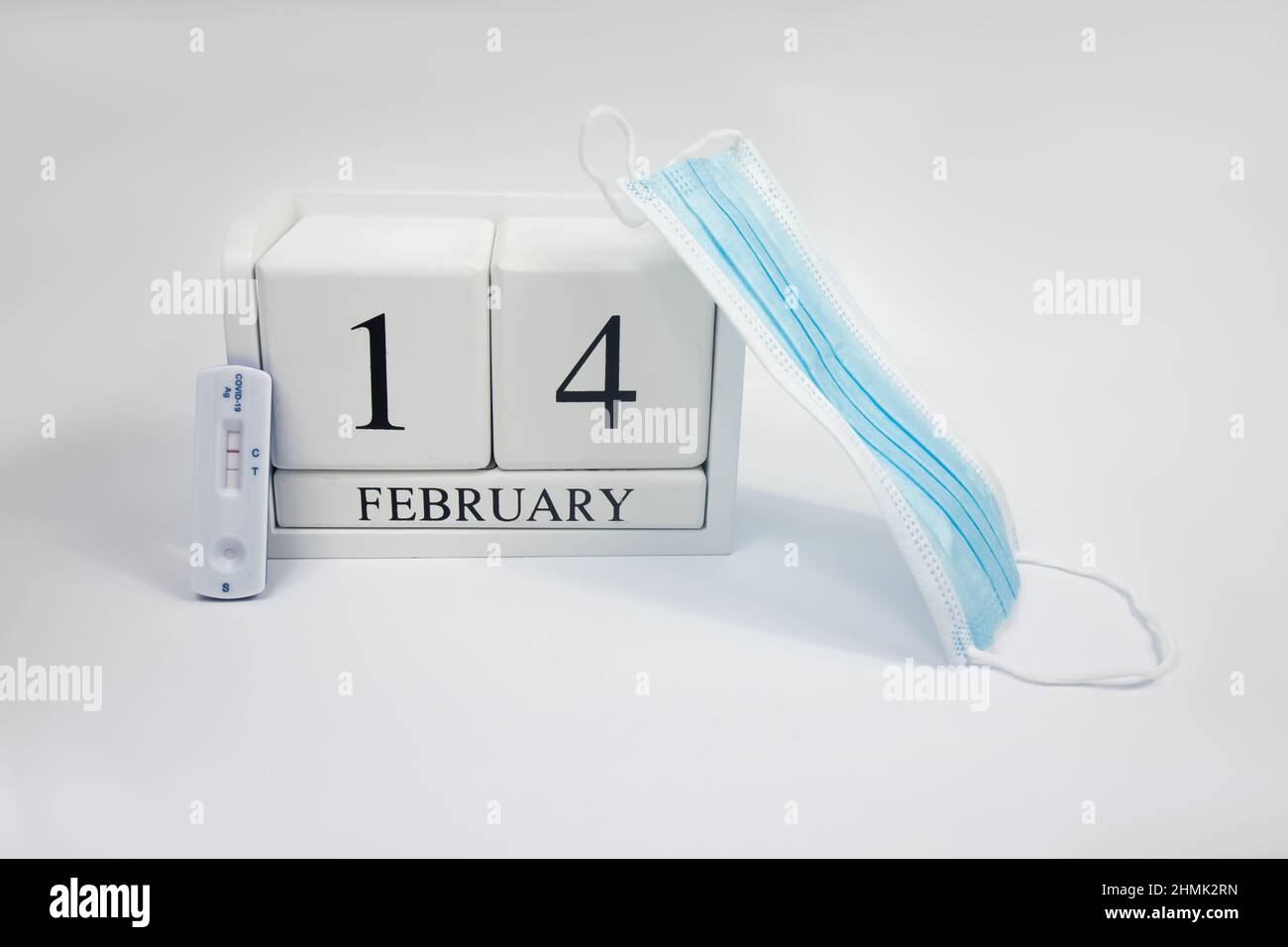 Calendario febbraio 14 legno bianco su sfondo bianco positivo prova covid e maschera medica. Giorno San Valentino concetto covid Foto Stock