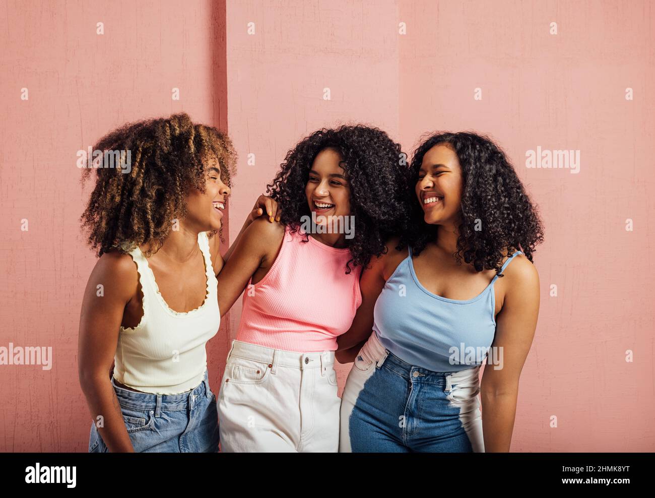 Femmine con capelli ricci che si guardano in studio su sfondo rosa Foto Stock