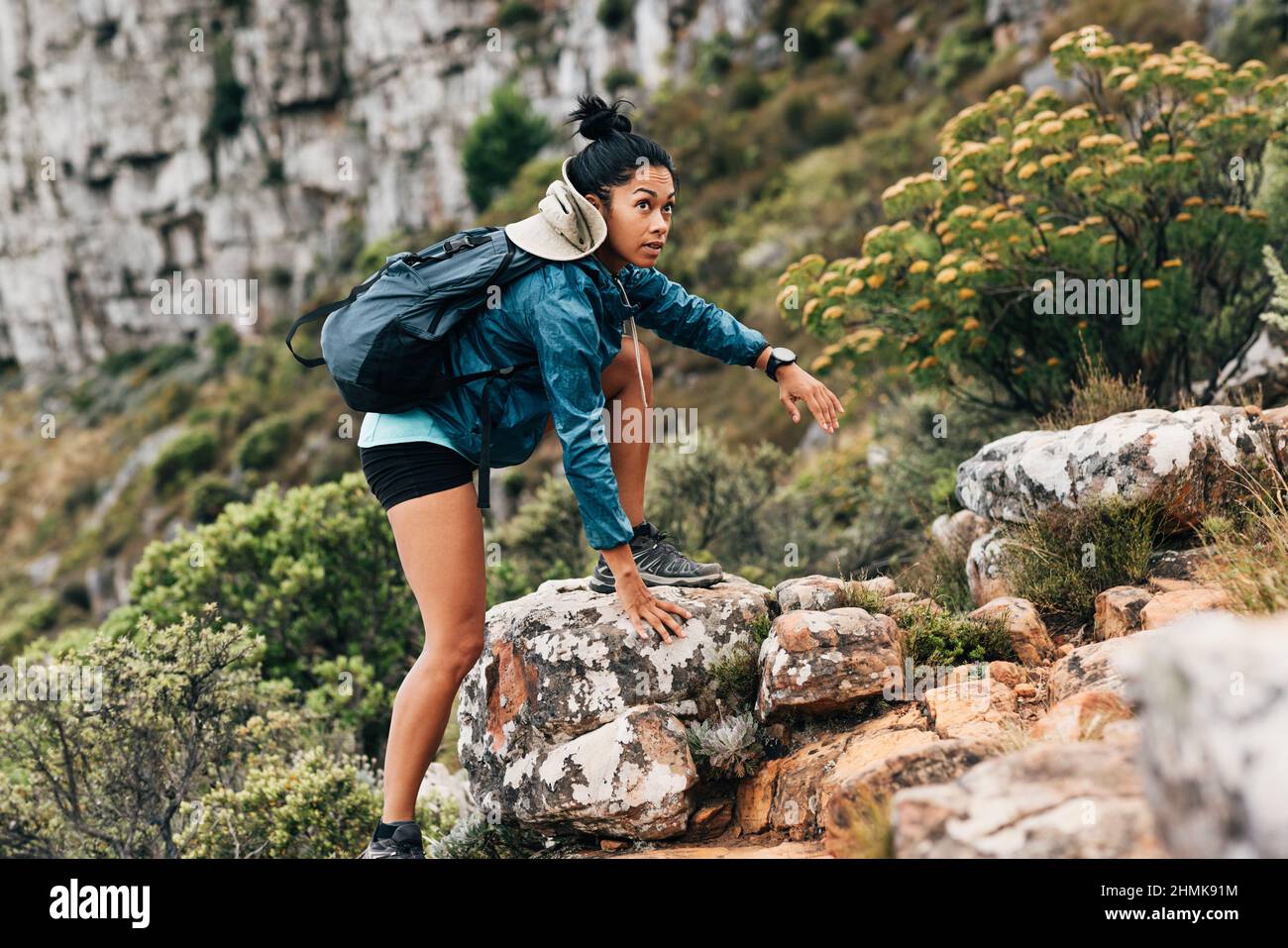 Donna escursionista che sale su una roccia. Giovane donna in abbigliamento sportivo con zaino escursioni su terreno di montagna. Foto Stock