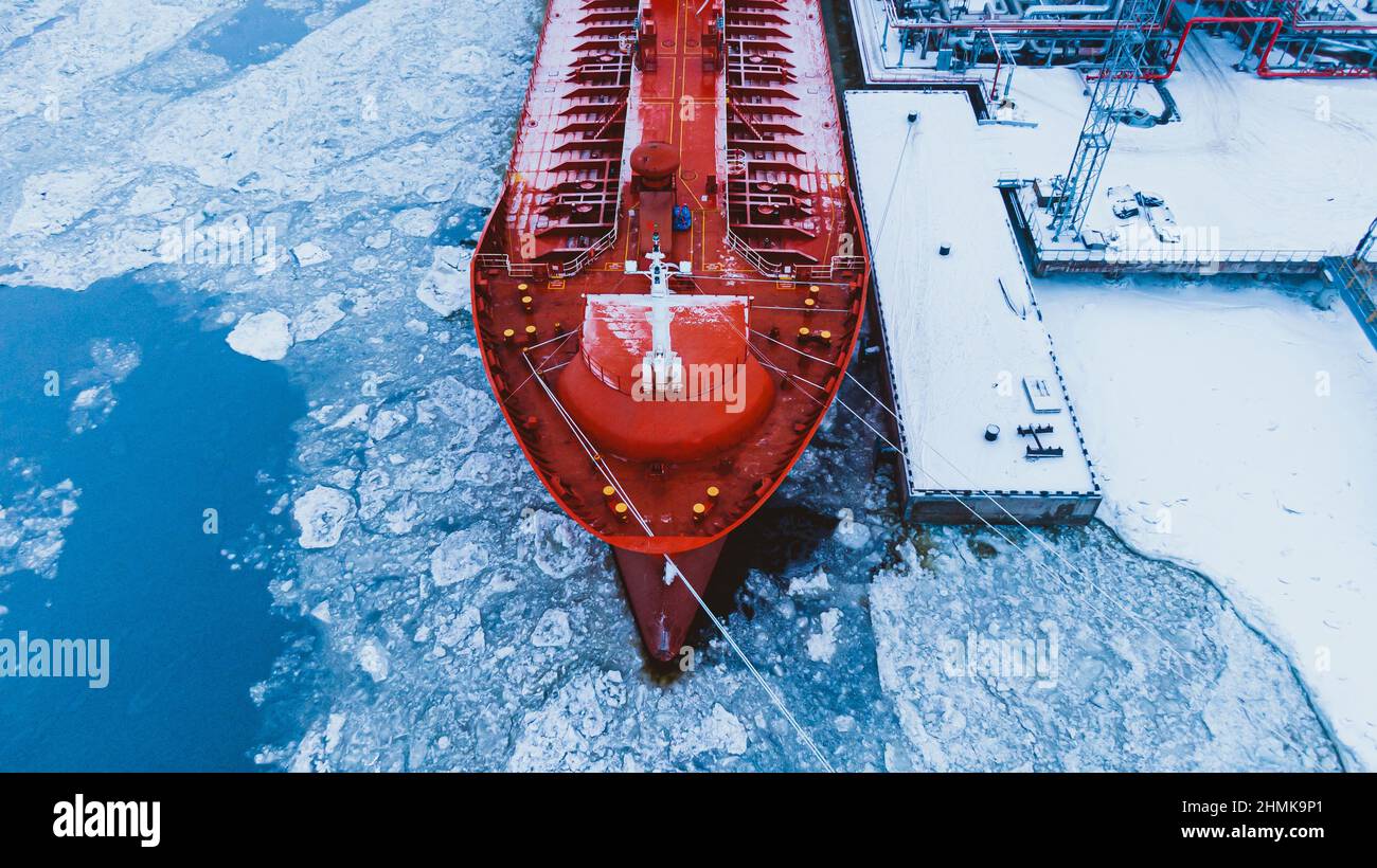 Spedizione di olio su grande petroliera rossa dal sistema di pompaggio terminale su acqua coperta con strato spesso di ghiaccio rotto in vista aerea ghiacciata invernale Foto Stock