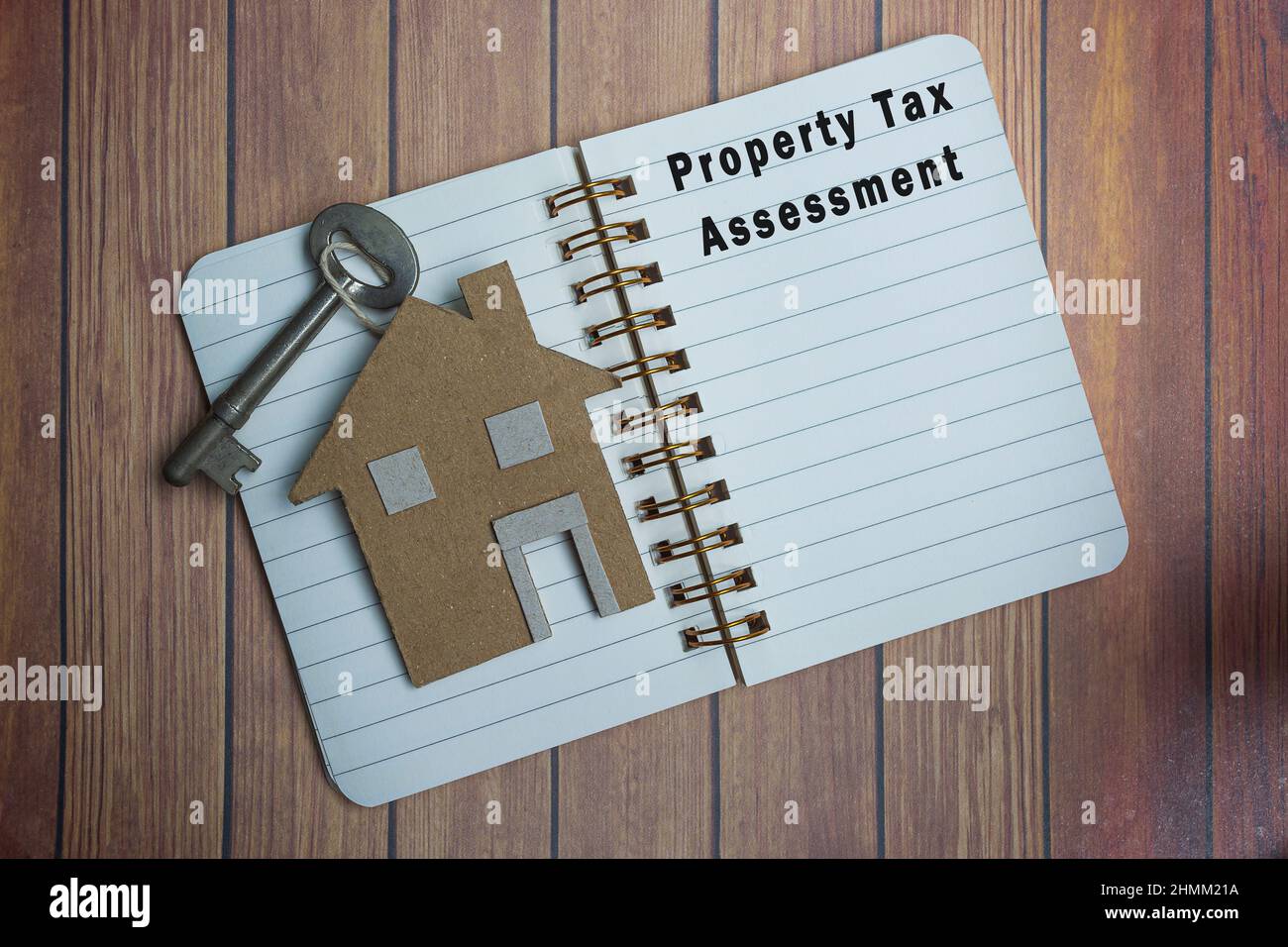 Testo di valutazione delle imposte sulla proprietà su un libro di note con modello di casa e chiave su scrivania in legno. Concetto di imposta Foto Stock