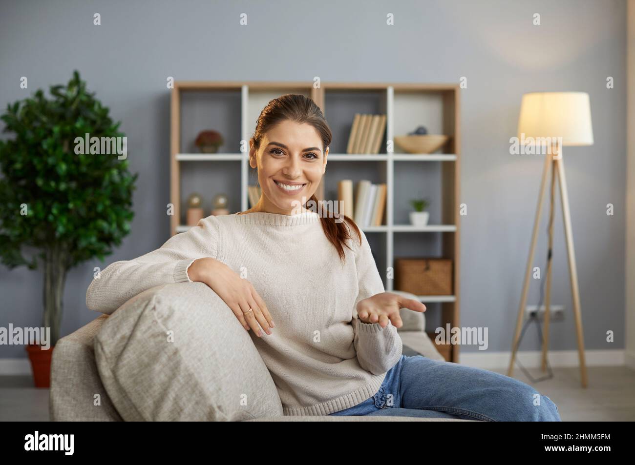 Donna amichevole seduta a casa di fronte alla webcam e lavorare in remoto o parlare con gli amici online. Foto Stock
