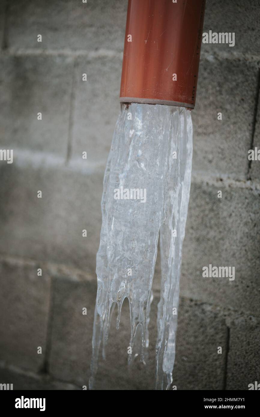Colpo verticale di acqua che esce da un tubo rosso Foto Stock