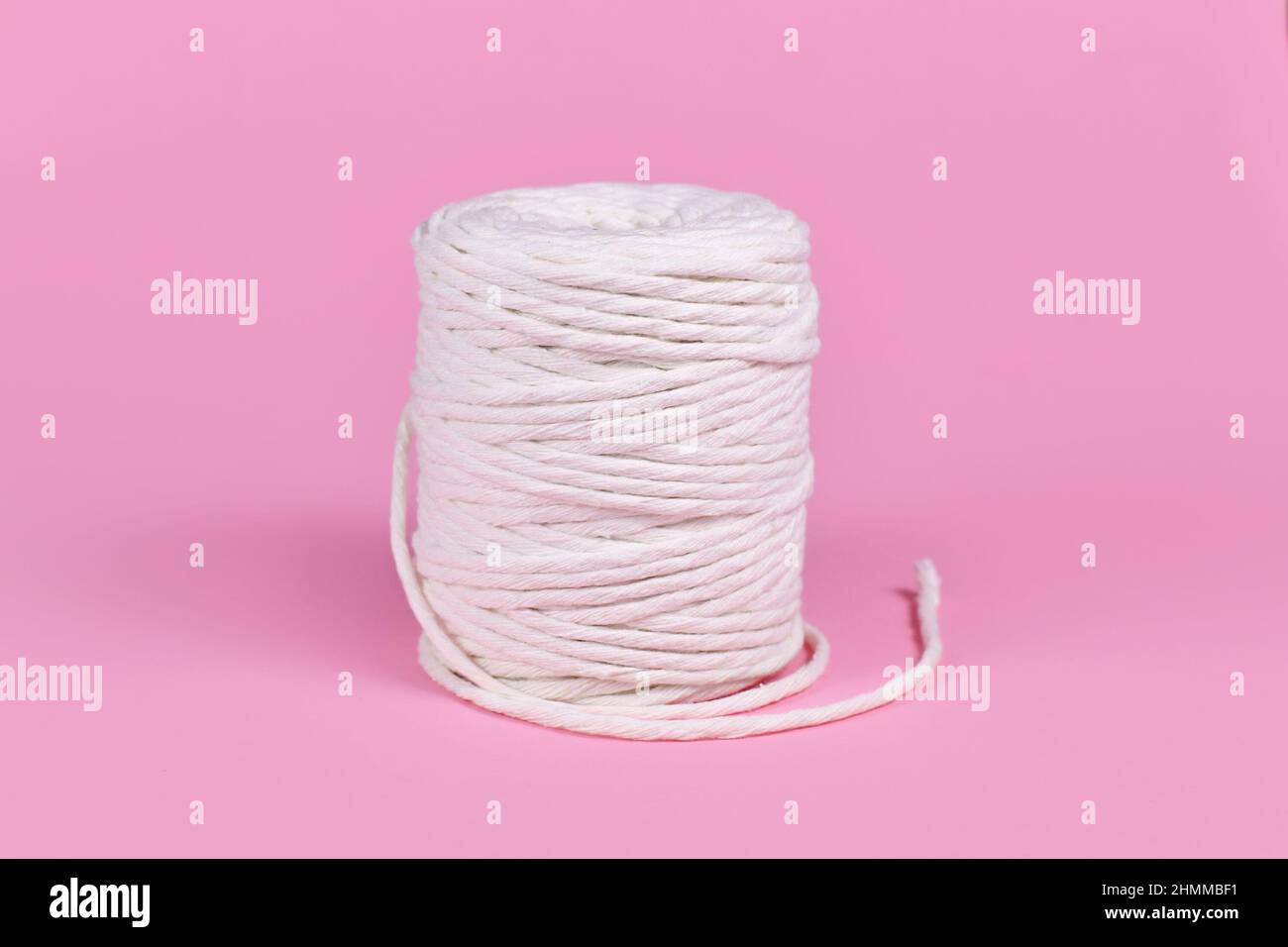 Rotoli di filo di macrama di cotone per la lavorazione su sfondo rosa Foto Stock