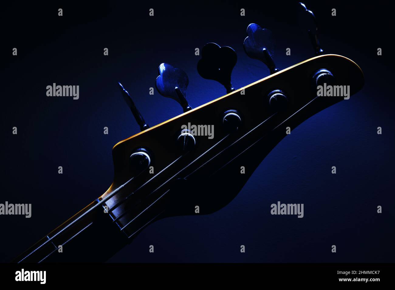 Primo piano della testa di cinque corde di chitarra basso, forme evidenziate. Foto Stock
