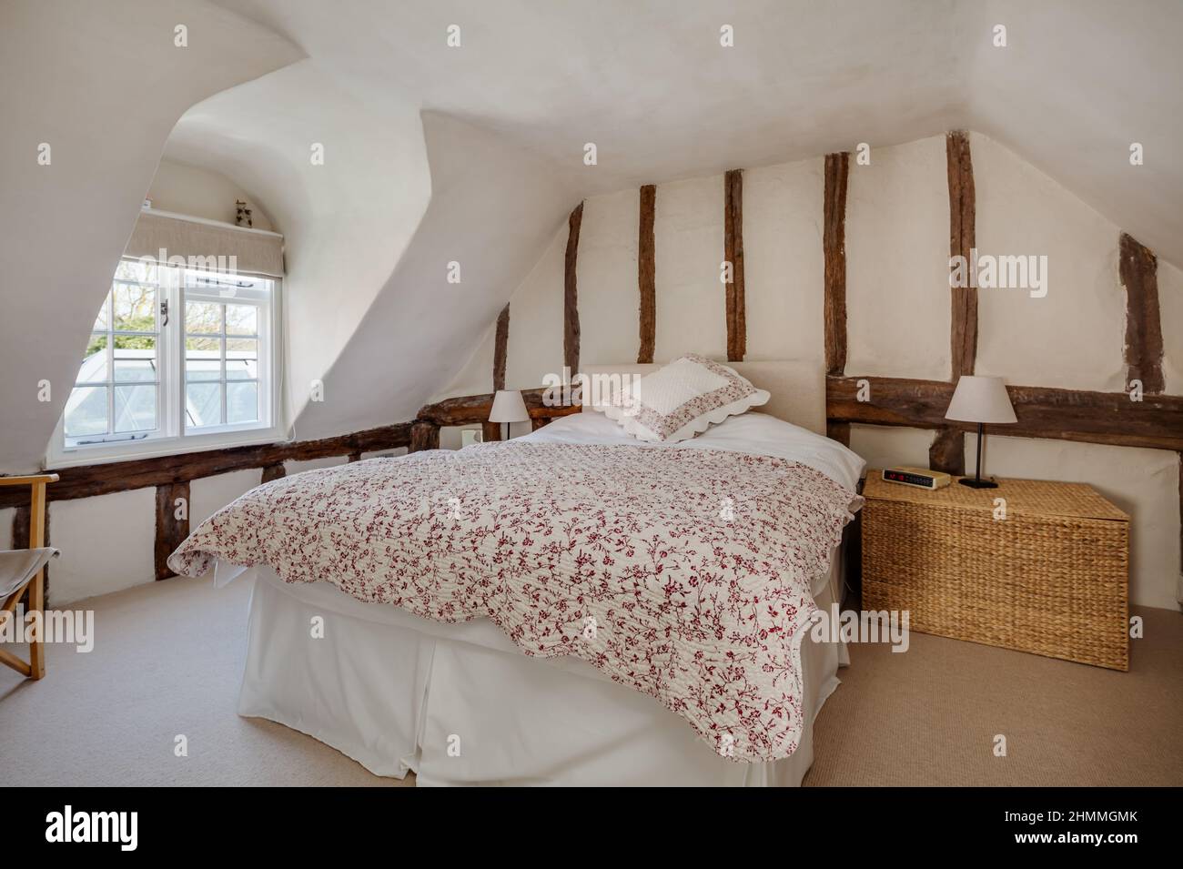 Great Chesterford, Essex - Aprile 3 2017 - attraente camera da letto ordinata con travi e travi a vista all'interno di un vecchio cottage con soffitti inclinati Foto Stock