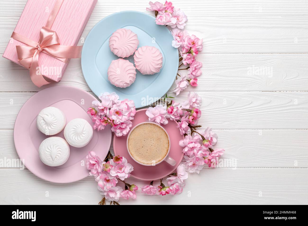 8 marzo Card. Cibo e bevande sfondo. Caffè e dessert su un tavolo di legno bianco. Fiori di primavera, fiori di ciliegio, bouquet rosa. Stile di vita. F Foto Stock