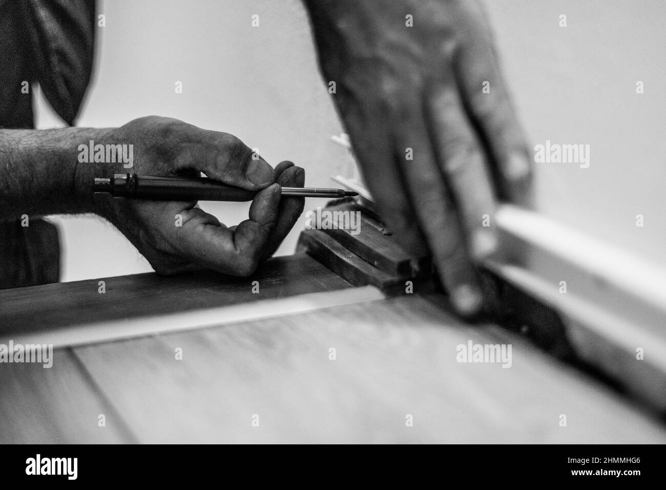 Uomo che installa un vassoio per cavi e che effettua le misurazioni con le mani e la matita per lavori di precisione e professionali. Foto Stock
