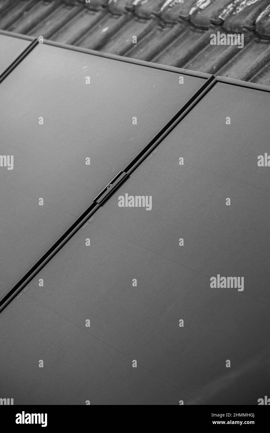 Primo piano di un'installazione di una serie di pannelli solari, installato sulla parte superiore di una casa con tegole. Foto Stock