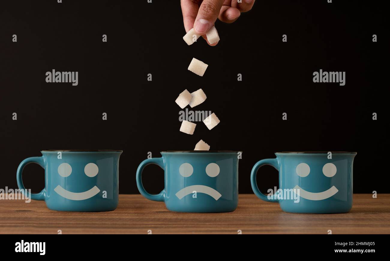 Foto ravvicinata della tazza da caffè e dell'aggiunta di zucchero a mano. Concetto di diabete e dipendenza dallo zucchero. Foto Stock