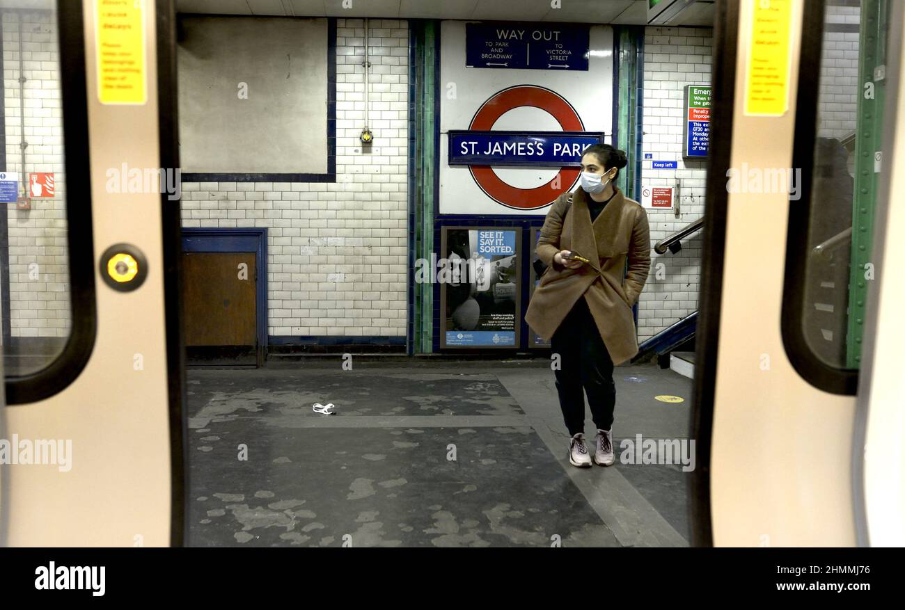 Londra, Inghilterra, Regno Unito. London Underground: Passeggero in attesa sulla piattaforma con maschera COVID, gennaio 2022 Foto Stock