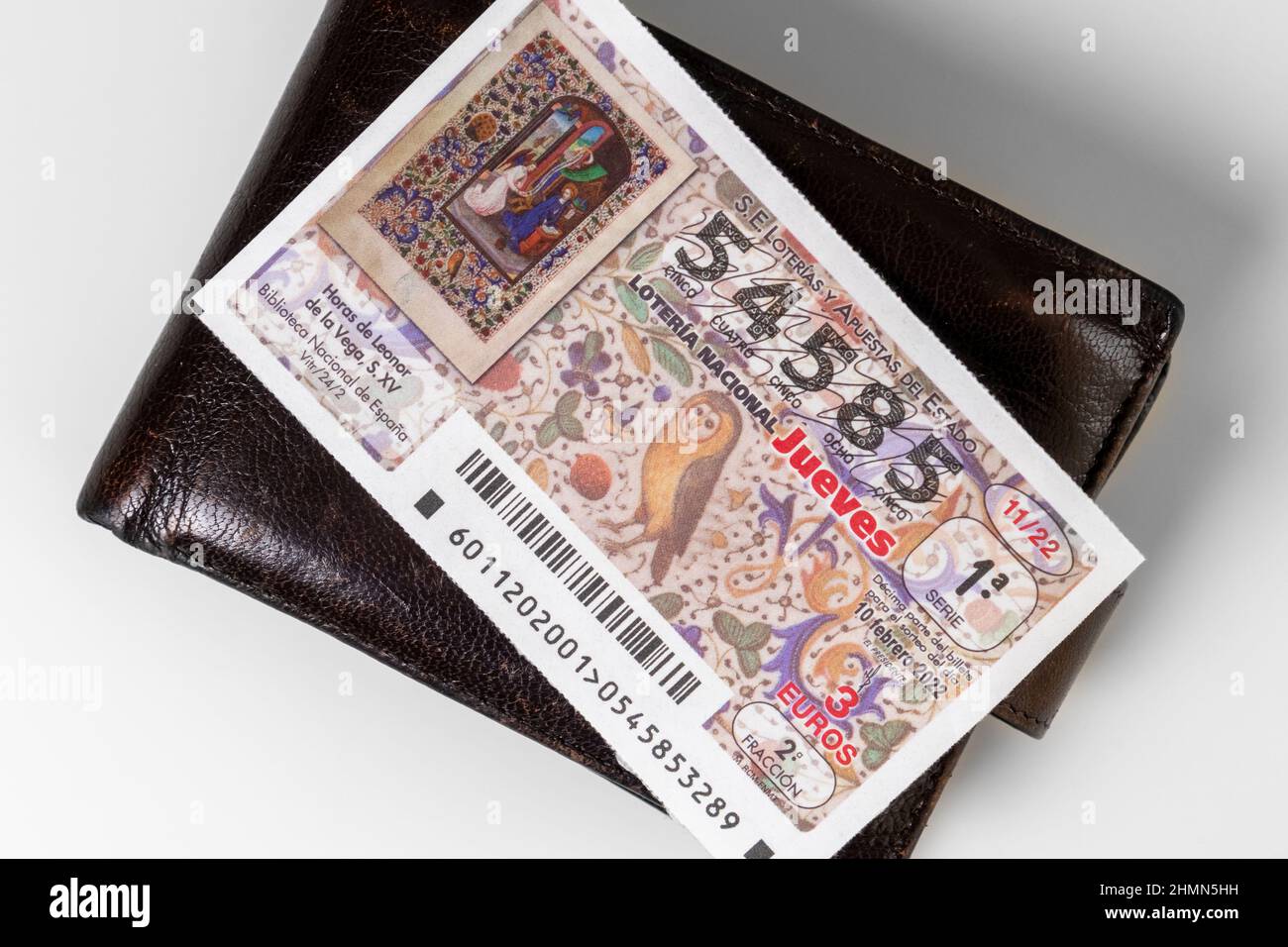 Oviedo, Spagna, 11 febbraio 2022: Primo piano del biglietto della lotteria nazionale spagnola su un portafoglio in pelle marrone su sfondo bianco Foto Stock