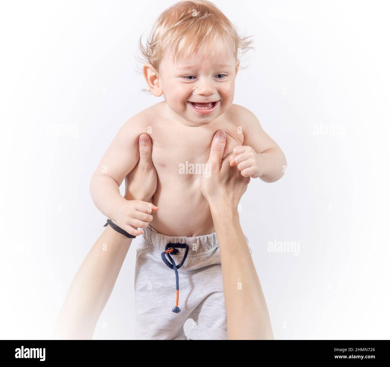 Un bambino ride fra le braccia di una madre che lo solleva su sfondo bianco Foto Stock