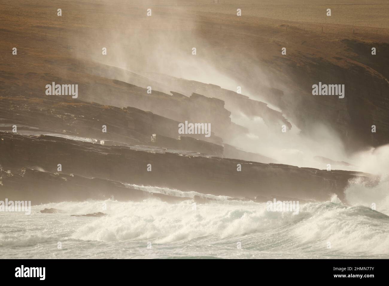 Onde illuminate dal sole che si infrangono sulla costa rocciosa, le isole Orkney Foto Stock