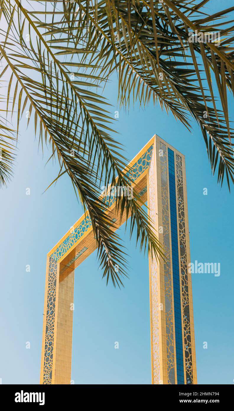 Verticale Foto di alta qualità. Vista della cornice di Dubai su Sunny Blue Sky sotto Palm Branches. Dubai Frame è un punto di riferimento architettonico nel Parco Zabeel, Dubai Foto Stock