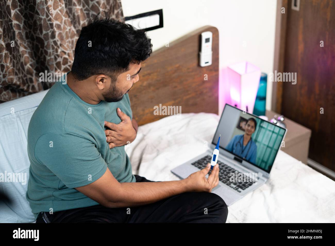 Uomo malato indiano che parla in videochiamata da medico di consulenza sul portatile in camera da letto - concetto di assistenza sanitaria, consultazione online e telemedicina Foto Stock