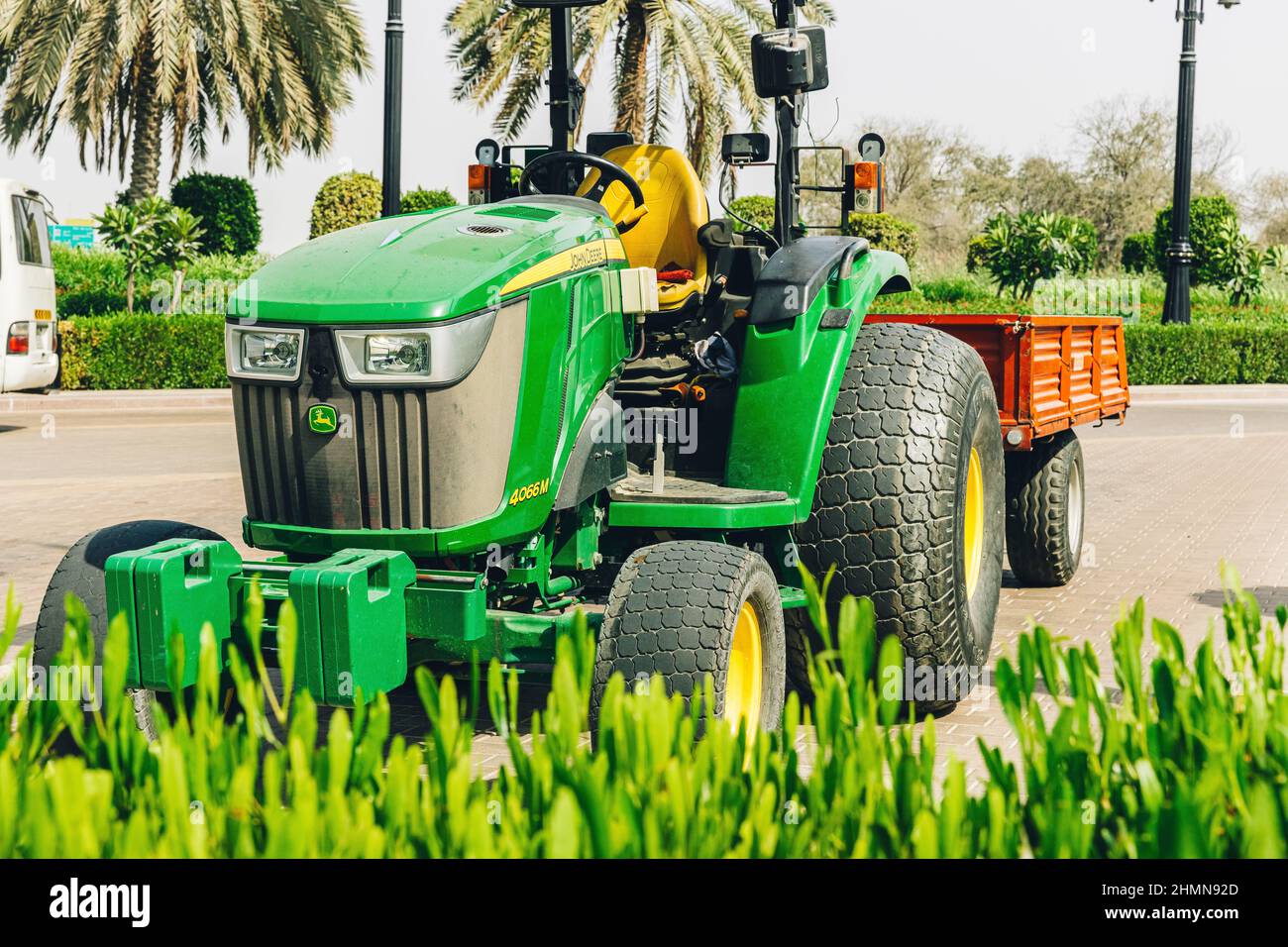 Dubai, Emirati Arabi Uniti - 25 maggio 2021: Trattore John Deere Compact Utility 4066M con rimorchio parcheggiato sul sentiero nel parco. Trattore multiuso compatto Foto Stock