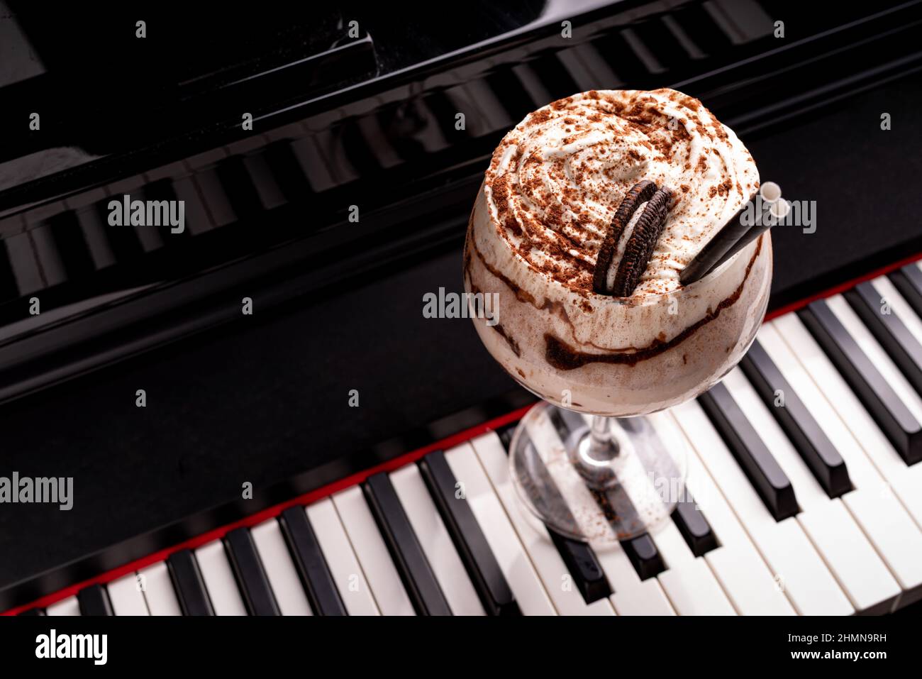 Cocktail dolce e alcolico al cioccolato guarnito con biscotto su una tastiera a piano in un night club Foto Stock