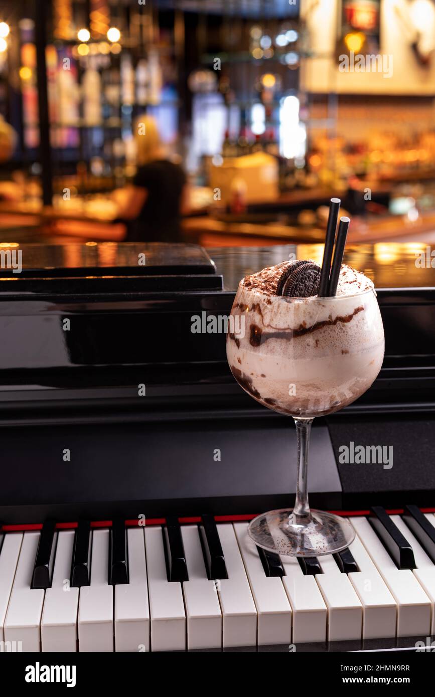 Cocktail dolce e alcolico al cioccolato guarnito con biscotto su una tastiera a piano in un night club Foto Stock