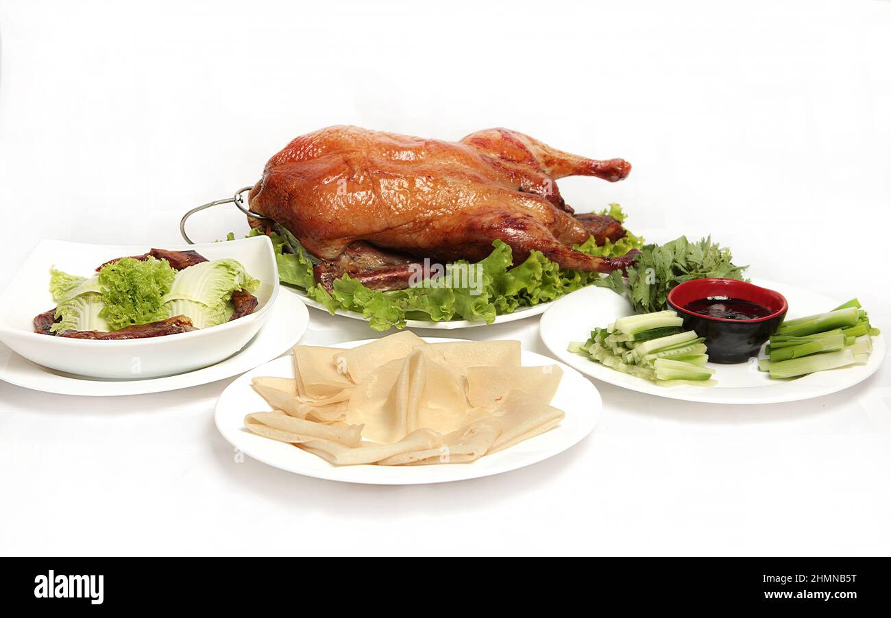 Anatra di Pechino, anatra croccante fritta cinese, servita con salsa di hoisin, frittelle e verdure verdi su sfondo bianco. Foto Stock