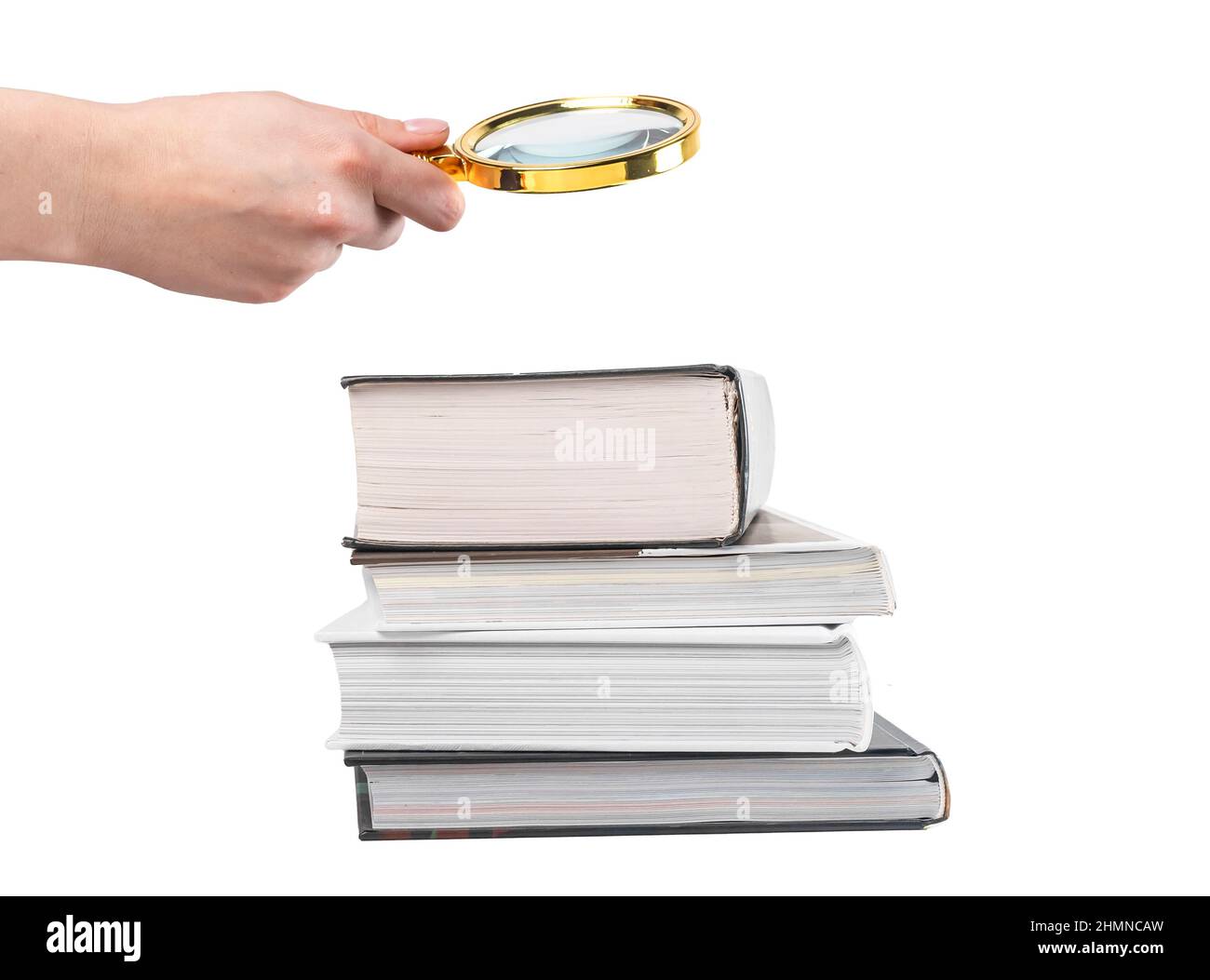 Mano che tiene la lente di ingrandimento sopra i libri impilano isolato su sfondo bianco. Ricerca e studio dettagliato del concetto di informazione. Foto di alta qualità Foto Stock