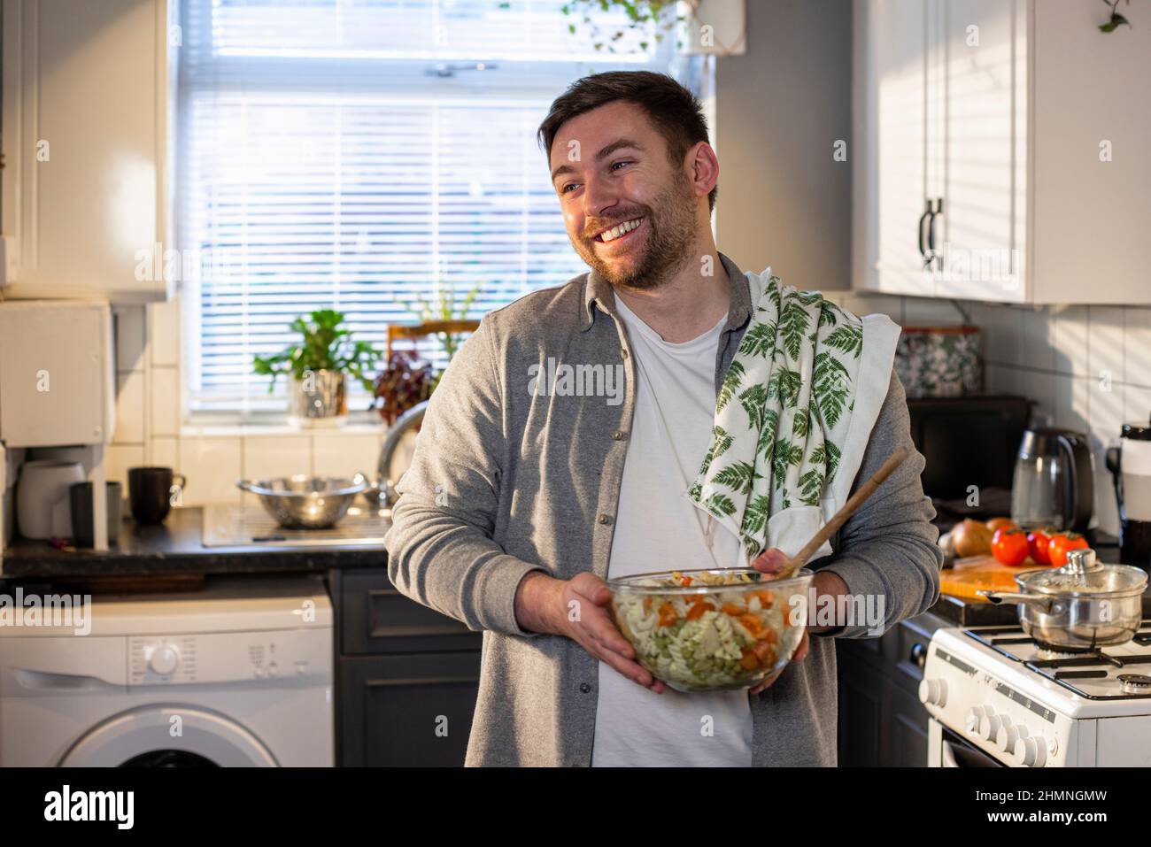 Un colpo di fronte di un uomo caucasico in piedi nella sua cucina, ha fatto una ciotola di pasta per pranzo. Foto Stock
