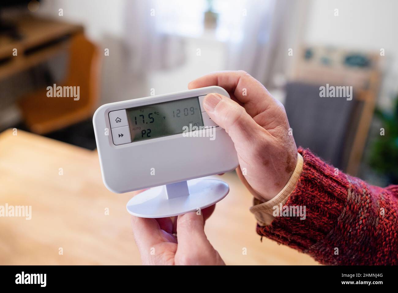 Un punto di vista girato di un uomo irriconoscibile che tiene un termostato nella sua casa. Foto Stock