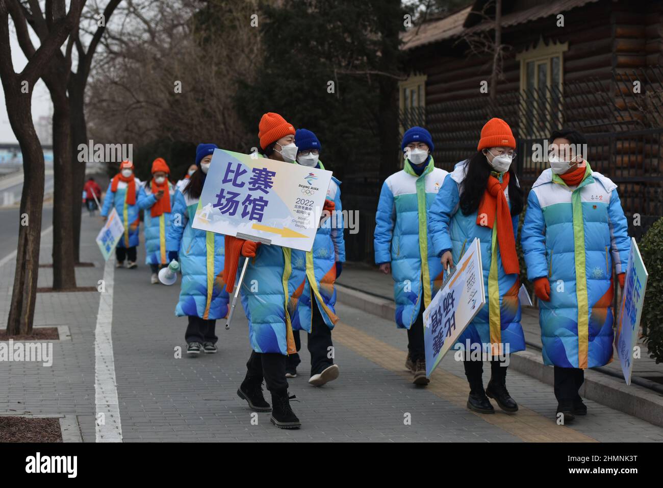 Pechino, Cina. 11th Feb 2022. I volontari che indossano maschere per i Giochi Olimpici invernali del 24th camminano vicino al Nido degli Uccelli a Pechino dopo aver completato il loro lavoro insigns.A CCTV News programma incentrato sui volontari delle Olimpiadi invernali di Pechino. Secondo il suo rapporto, più di 18.000 volontari hanno servito in luoghi diversi all'interno e all'esterno dei Giochi, diffondendo amicizia e calore in modi diversi. Credit: SOPA Images Limited/Alamy Live News Foto Stock