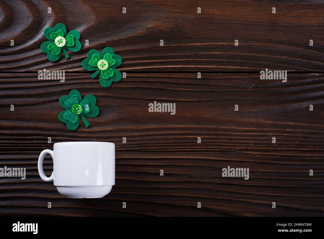 Tazza di caffè con tre foglie di shamrock fatte a mano su sfondo di legno Foto Stock