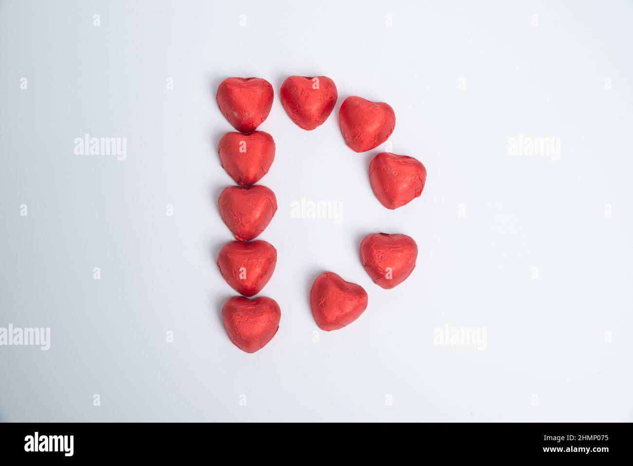 Caramelle al cuore rosso cioccolato sotto forma di lettera D per San Valentino su sfondo bianco Foto Stock