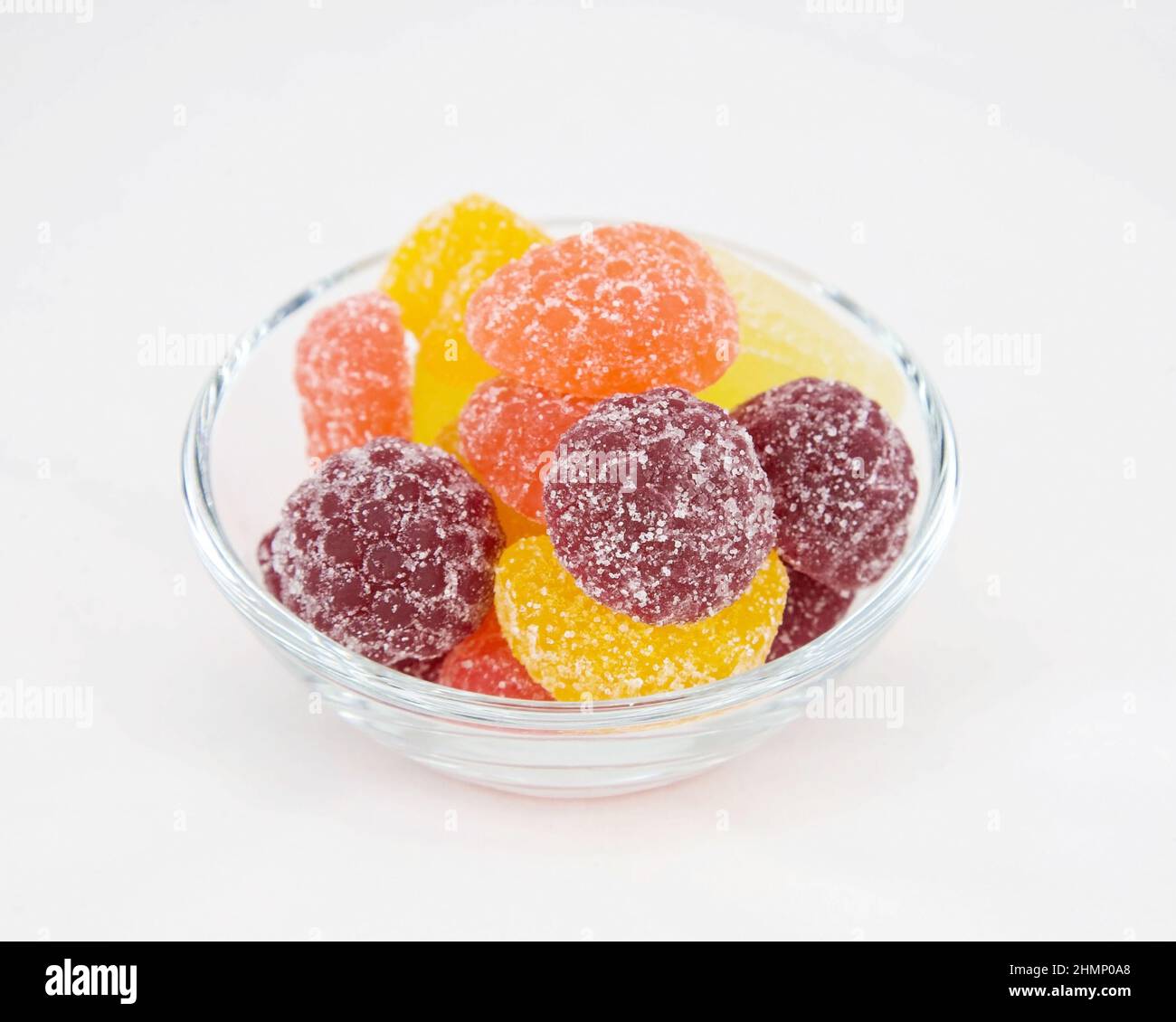 Marmellata multicolore a base di succo di frutta sotto forma di bacche e frutta in una tazza di vetro su sfondo bianco Foto Stock