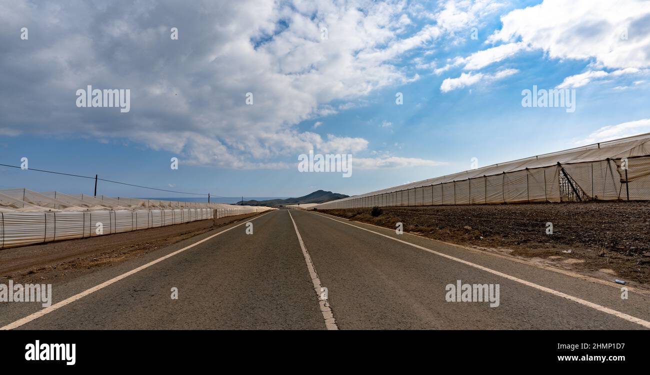 Una vista di un'autostrada che passa attraverso infinite grandi serre fatte di plastica nel deserto senza acqua della Spagna meridionale Foto Stock