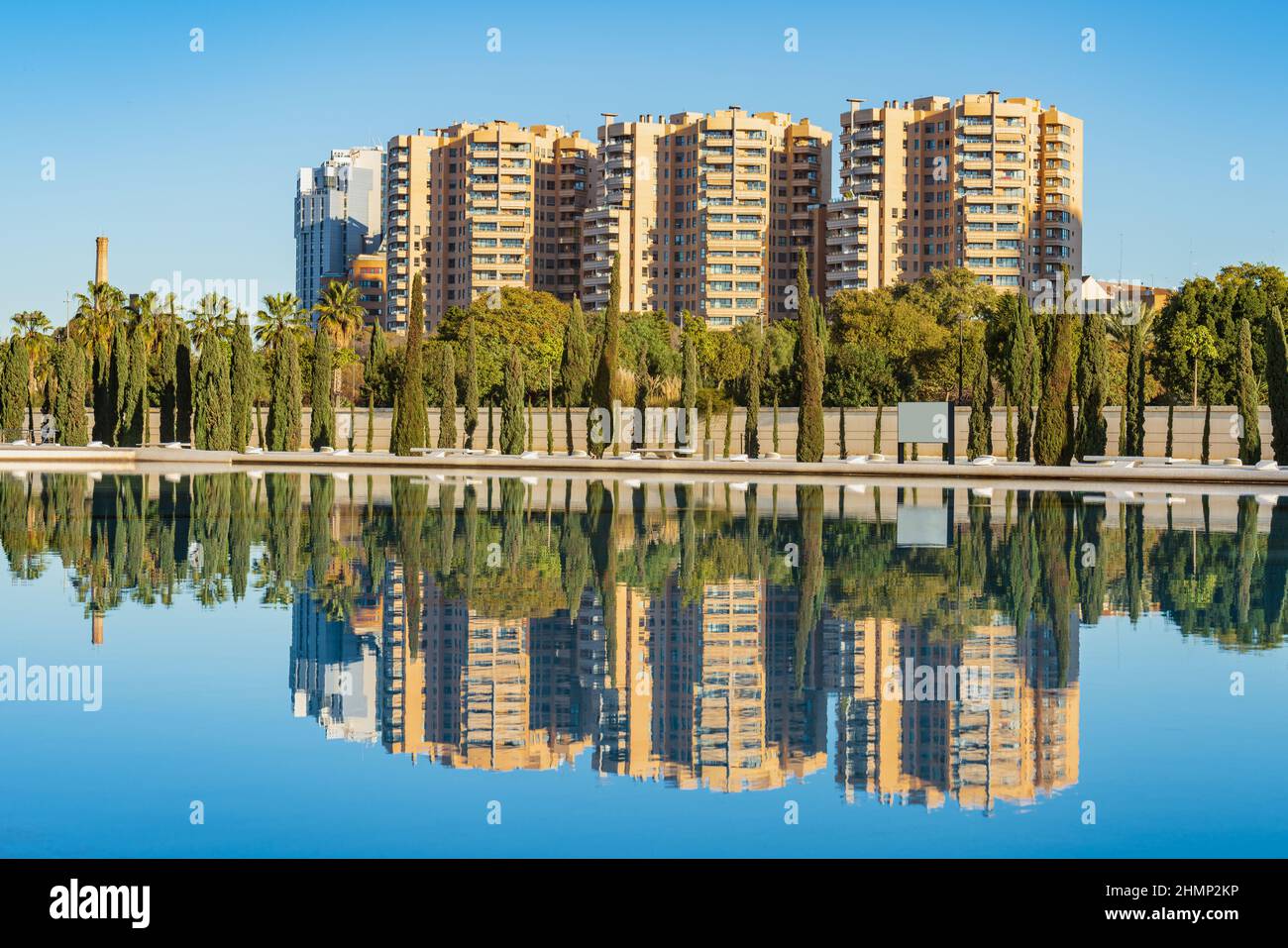 Un gruppo di edifici residenziali contro il cielo blu si riflette su una piscina Foto Stock