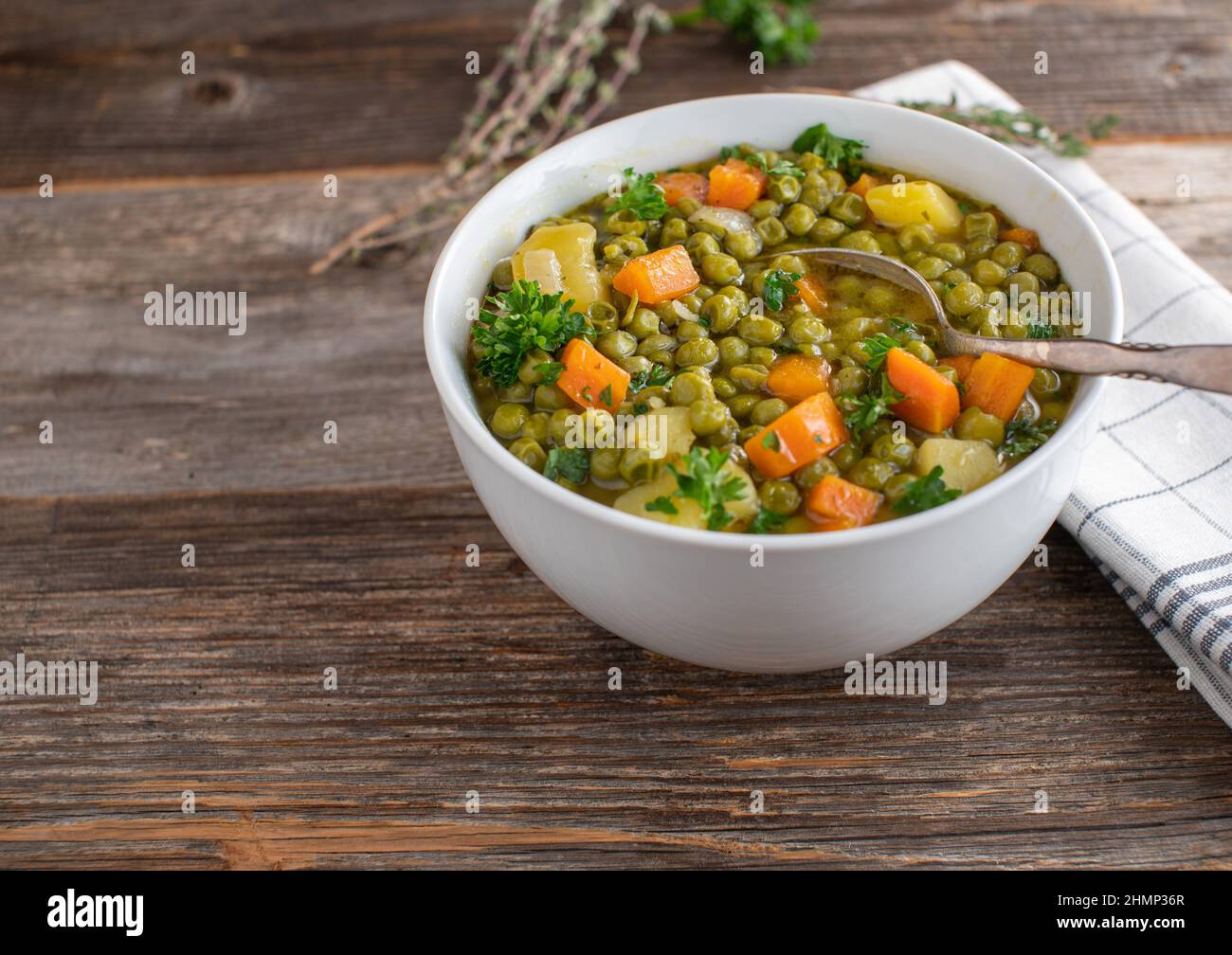 Zuppa di piselli vegani in una ciotola con cucchiaio isolato su tavola di legno con spazio copia Foto Stock