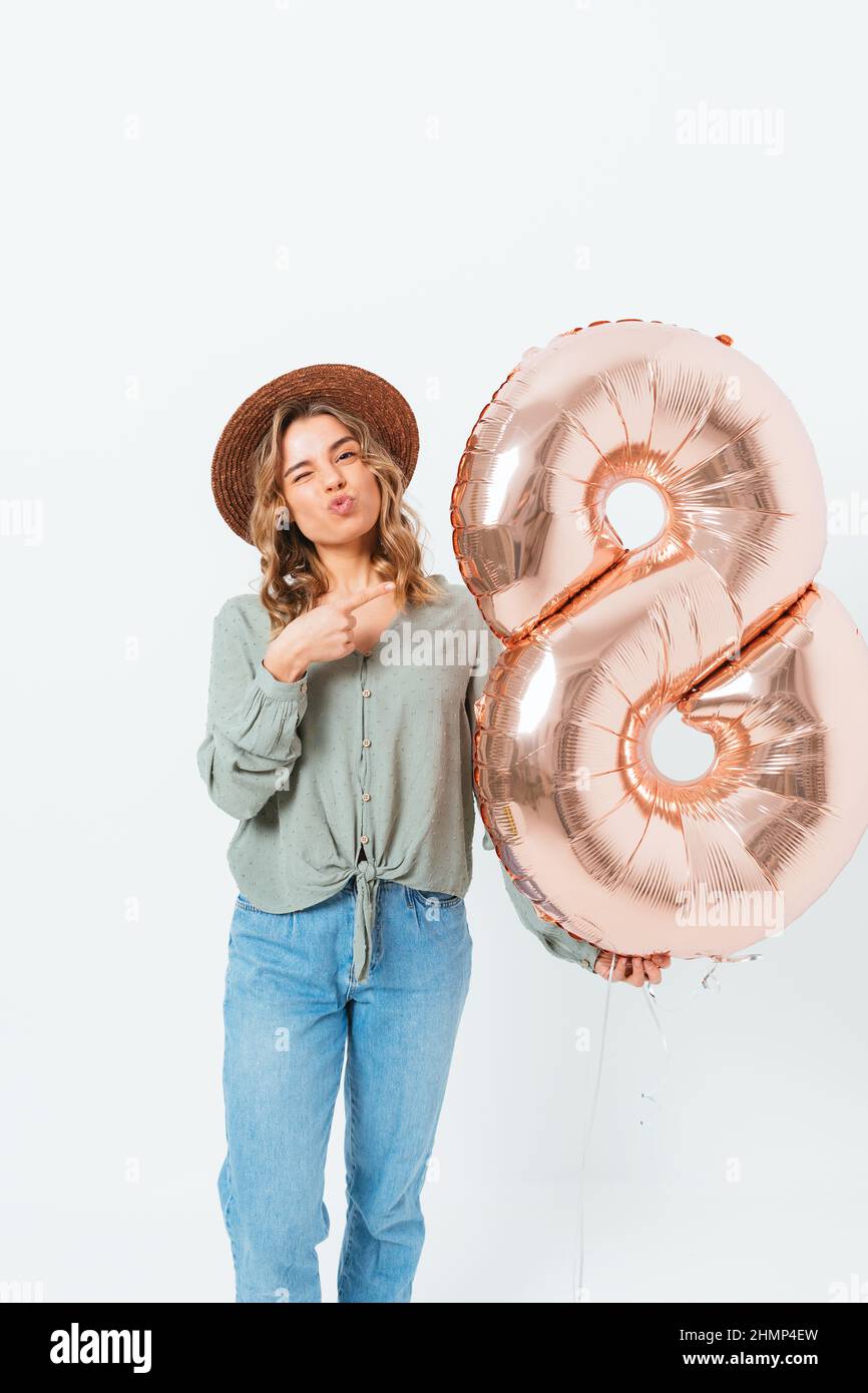 La giovane donna che tiene il pallone mentre si alza su sfondo bianco dello studio celebra la Giornata Internazionale delle Donne Foto Stock