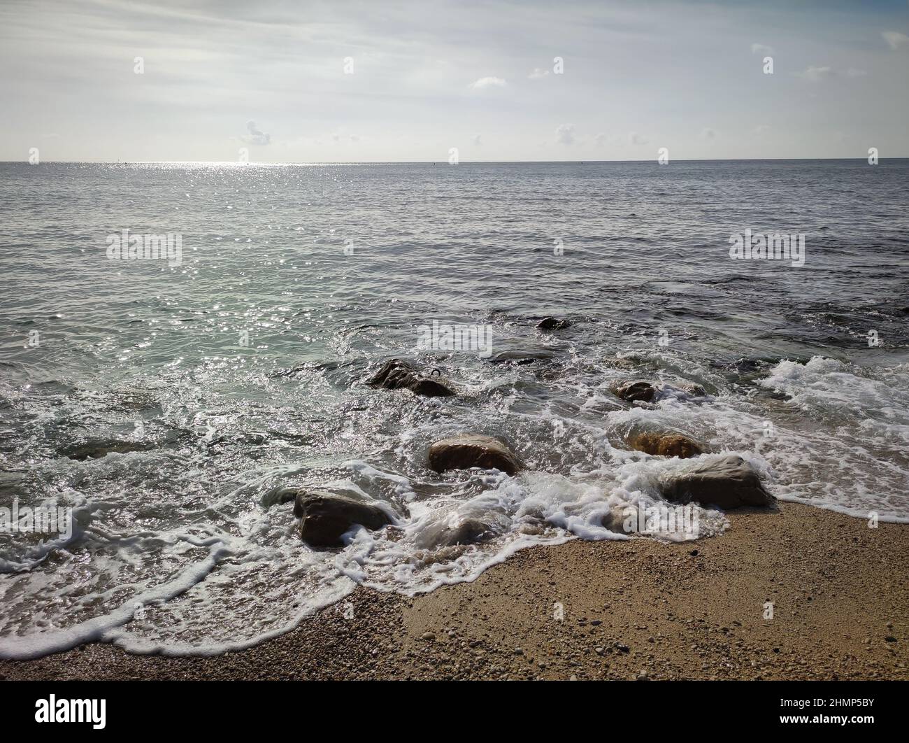 onda che viene a correre aground su pietre Foto Stock
