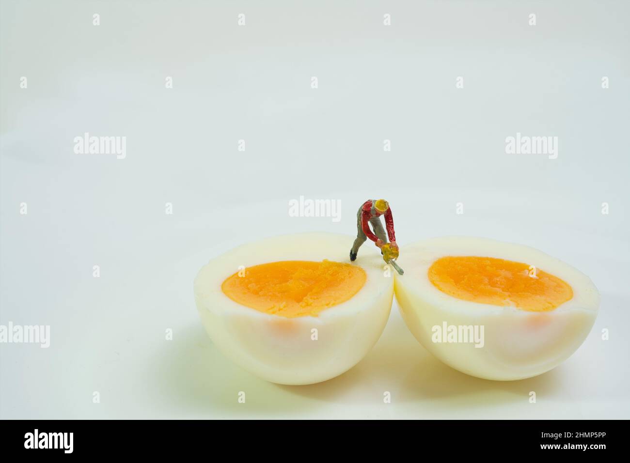 un lavoratore con una motosega si trova su due metà di uovo sode per dividerle, tagliandole aperte Foto Stock