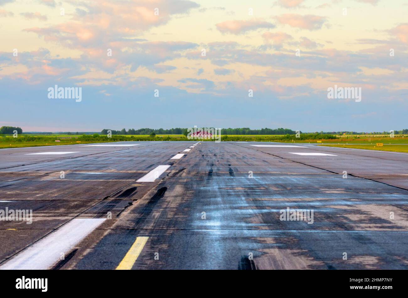 Alba con paesaggio aeroporto di pista bagnata con tracce di gomme su asfalto Foto Stock