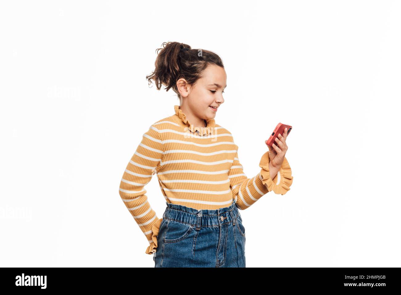 Giovane ragazza che ha una videochiamata sul suo cellulare mentre si trova su uno sfondo bianco isolato. Foto Stock