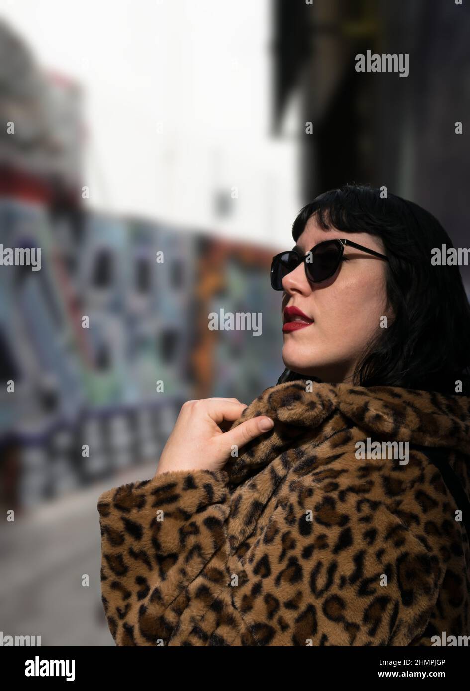 Ritratto di una giovane donna che indossa un cappotto in pelliccia sintetica con stampa leopardo e occhiali da sole Foto Stock