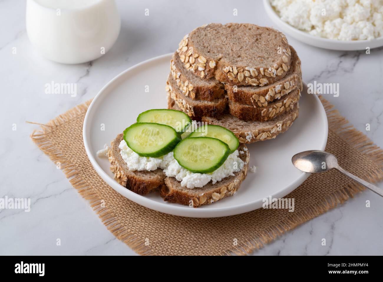 Fette di pane di segale con formaggio casereccio e cetrioli su sfondo bianco Foto Stock