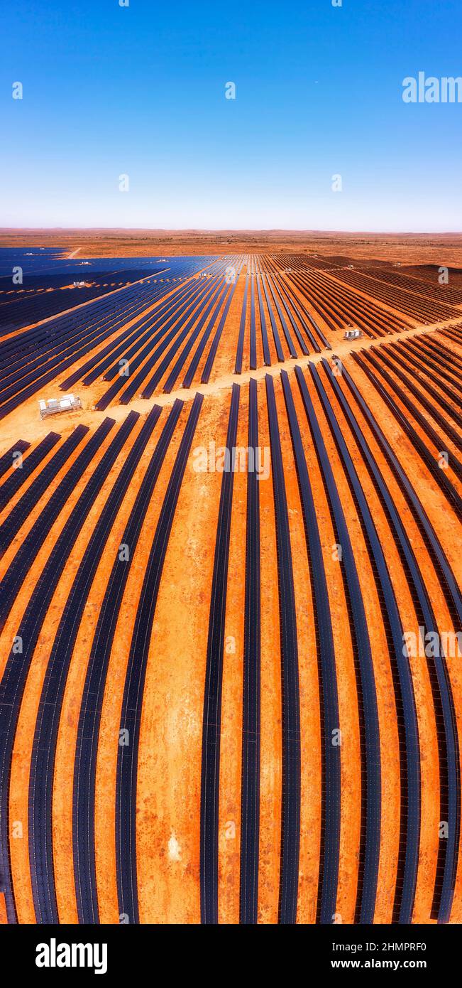 Linee di elementi pannelli solari di Broken Hill pianta solare su suolo rosso nell'entroterra australiano - panorama aereo verticale. Foto Stock